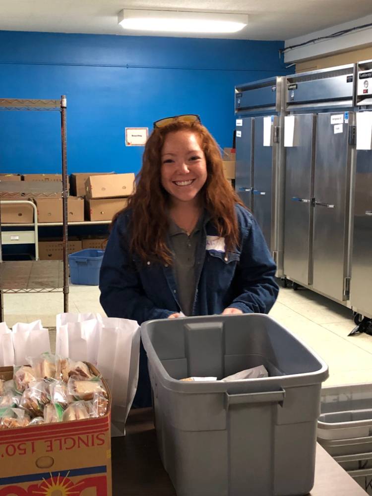 A volunteer smiles while volunteering at Kids' Food Basket.